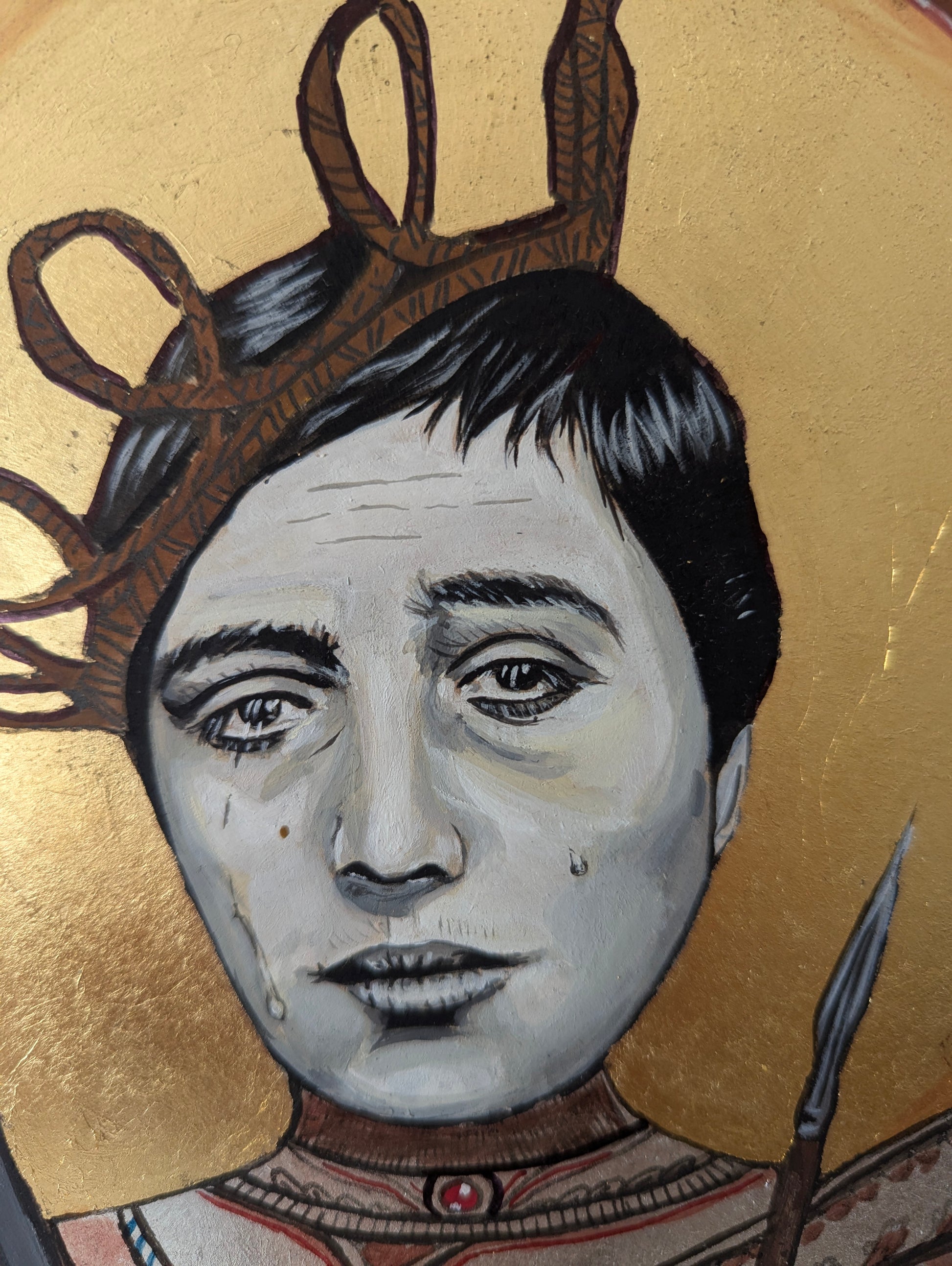 Detailed view of Joan of Arc’s iconic face inspired by silent film aesthetics, set against a luminous golden halo, with finely layered silver-painted armor on wood surface