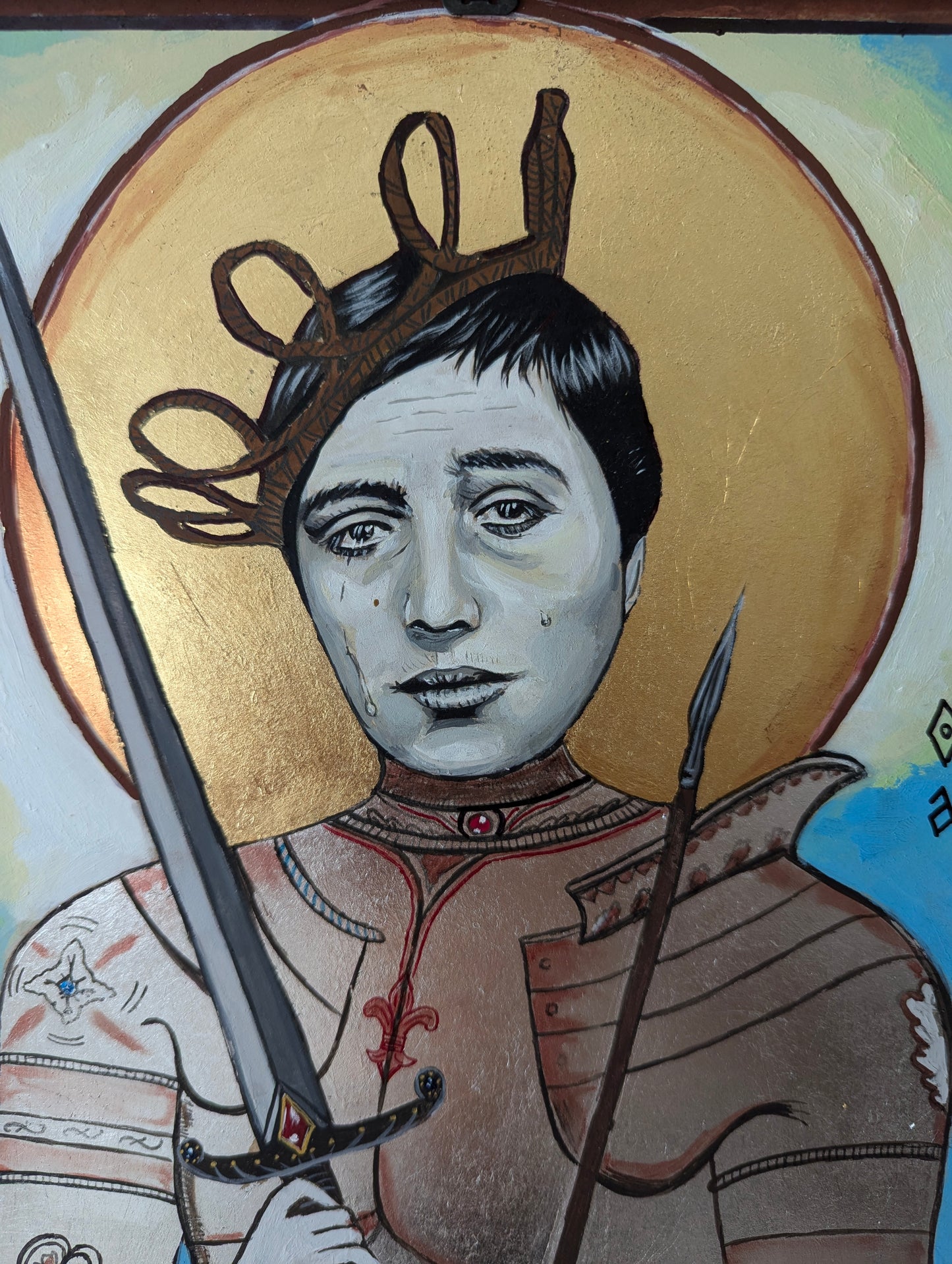 Close-up of sacred Joan of Arc artwork with cinematic facial expression, textured gold background, handcrafted iconography details, and polished silver paint accents